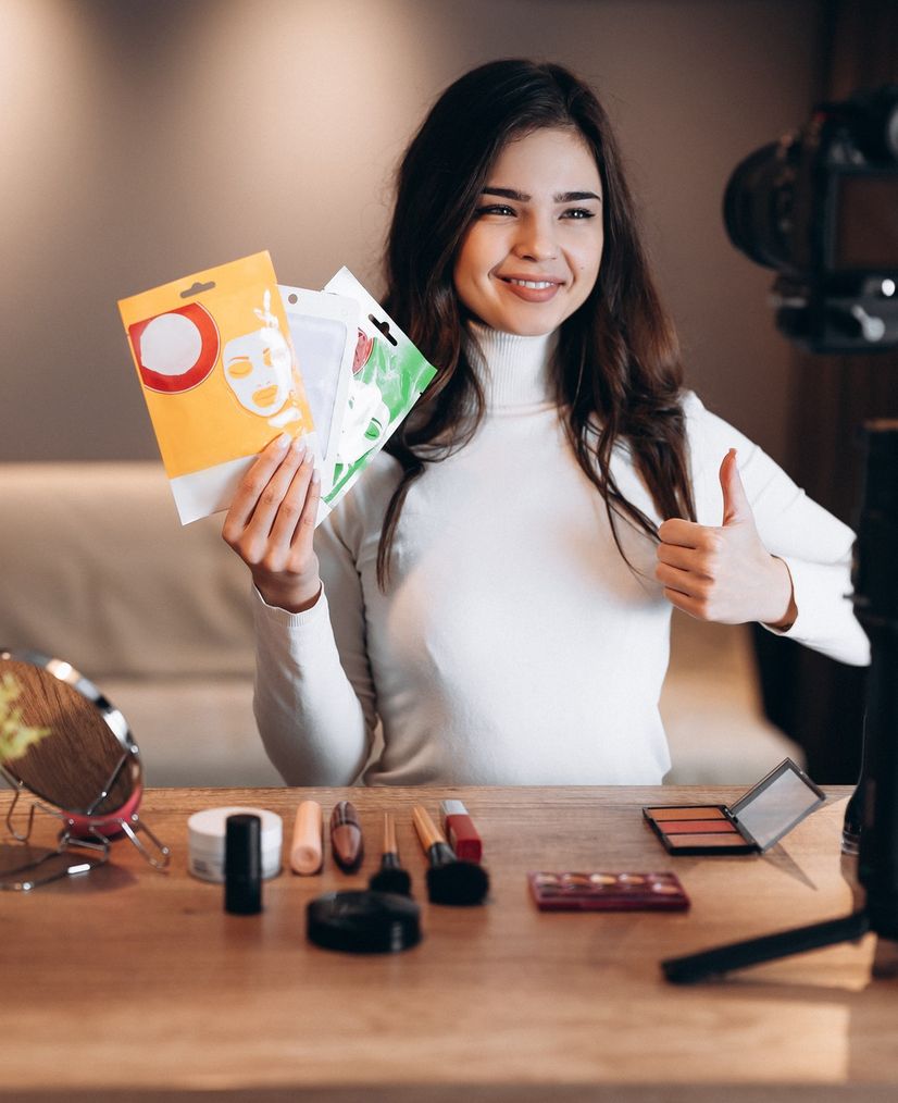 An actress holds up some products in front of a video camera